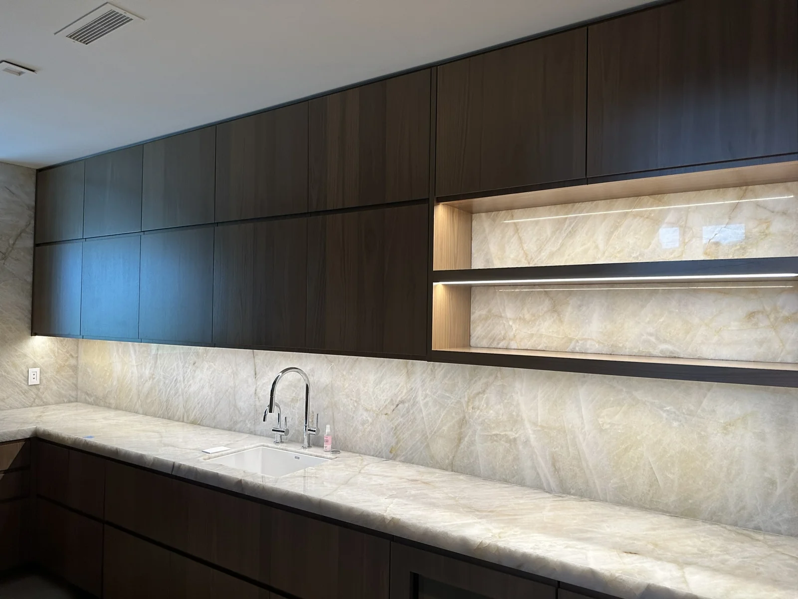 Kitchen cabinetry with integrated shelf and under-cabinet lighting